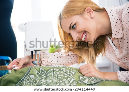 Happy female designer working on sewing machine