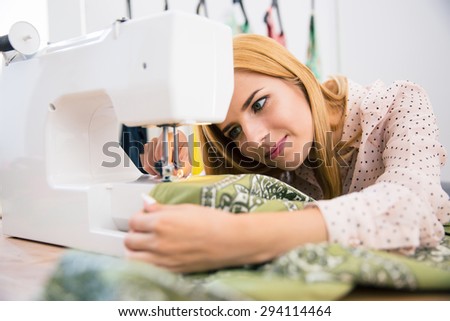Pretty female tailor using sewing machine in laundry