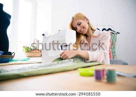 Happy fashion designer working on sewing machine