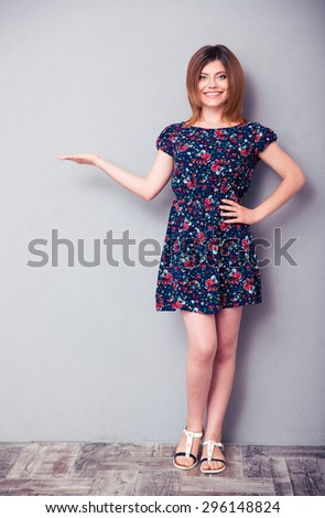 Full length portrait of a casual happy woman showing copyspace on the palm. Looking at camera