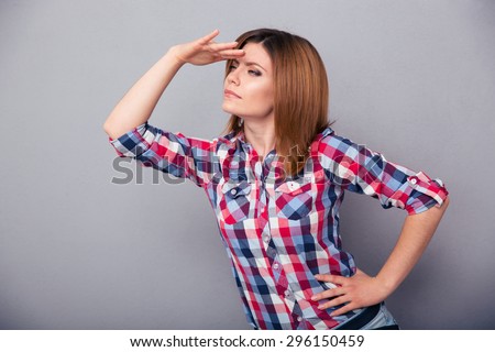 Young casual woman looking into the distance over gray background