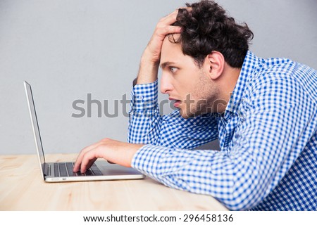 Side view portrait of a serious man sitting at the table and using laptop