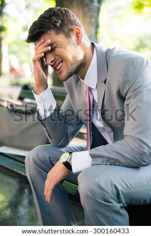 Portrait of depressed businessman sitting on the bench outdoors