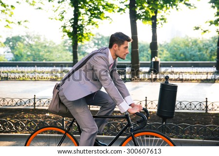 Businessman riding bicycle to work in city park