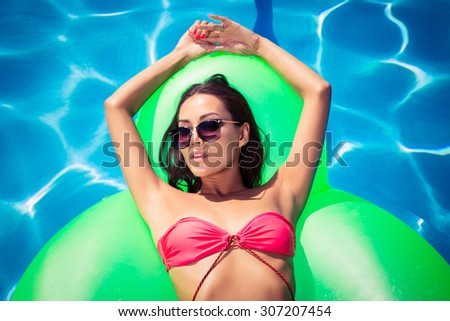 Portrait of attractive woman resting on air mattress in swimming pool