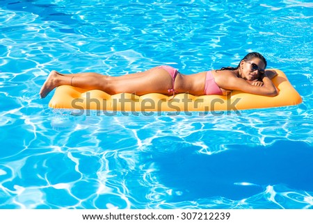 Young woman sunbathing on air mattress in the swimming pool