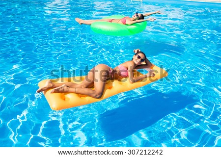 Portrait of a two women lying on air mattress in the swimming pool
