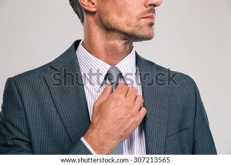 Closeup portrait of a businessman straightening his tie isolated on a white background