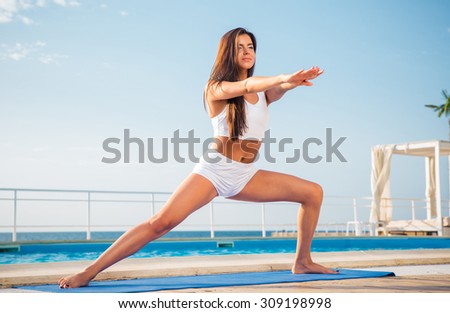 Portrait of a young woman doing stretching exercises on yoga mat outdoors in the morning