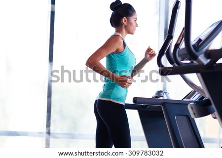 Fitness woman running on treadmill in gym