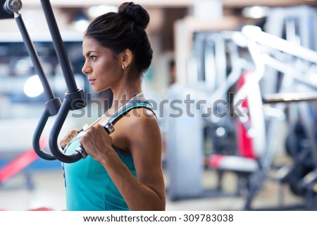 Side view portrait of cute woman workout on exercises machine in fitness gym