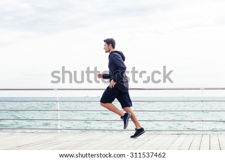 Side view portrait of a sports man running near sea