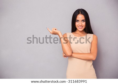 Portrait of a smiling girl showing finger away over gray background