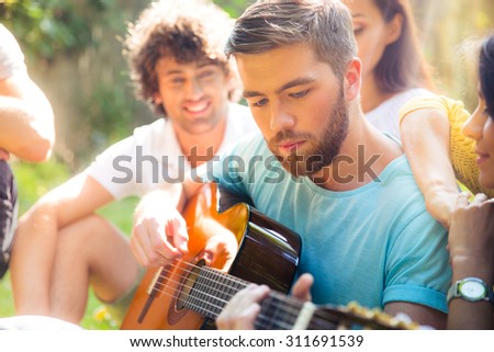 Group of a students with guitar resting outdoors