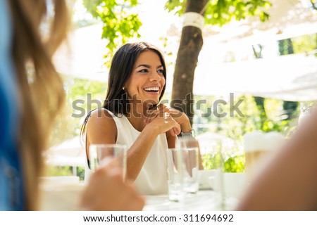 Portrait of a laughing woman sitting at the table in outdoor restaurant