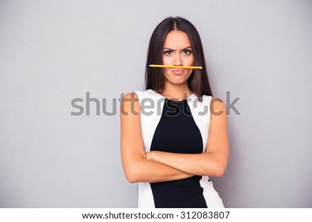 Portrait of a funny woman with pencil standing over gray background