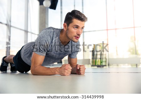 Portrait of a fitness man doing planking exercise in gym