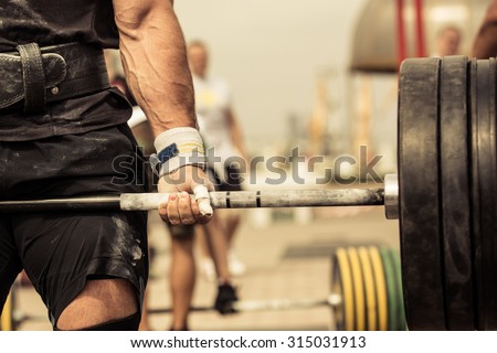 Closeup portrait of professional bodybuilder workout with barbell outdoors
