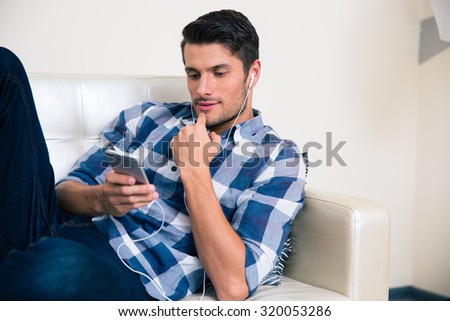 Portrait of a young man using smartphone on the sofa