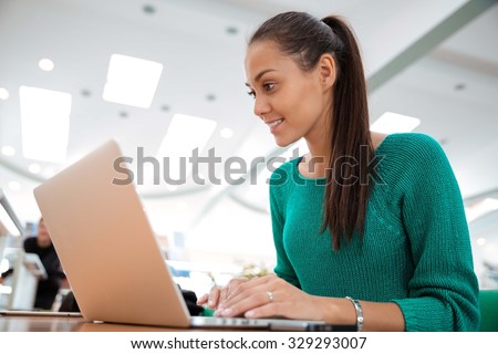 Portrait of a happy female student using laptop computer in university