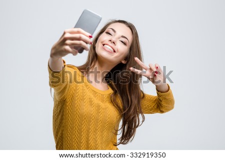 Portrait of a smiling cute woman making selfie photo on smartphone isolated on a white background