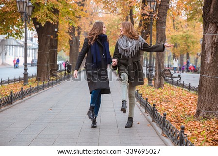 Portrait of a funny two girlfriends walking in autumn park