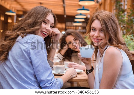 Portrait of a three girlfriends drinking coffee in cafe together