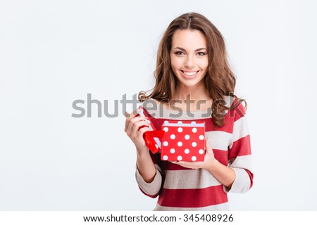 Portrait of a smiling cute woman opening gift box and looking at camera isolated on a white background