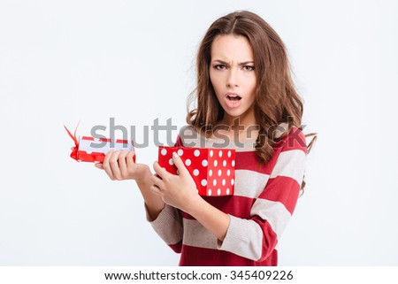 Portrait of unhappy woman opening gift box and looking at camera isolated on a white background