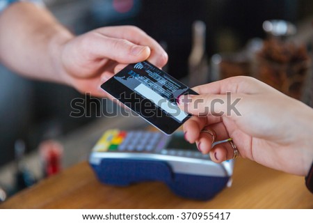 Closeup of two hands holding credit card for paying with reader