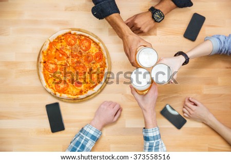 Top view of multiethnic group of young people drinking beer and eating pizza
