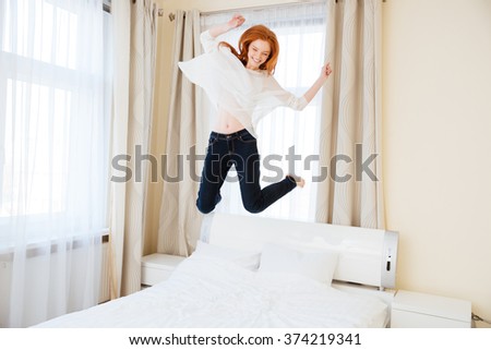 Cheerful young woman jumping on the bed at home