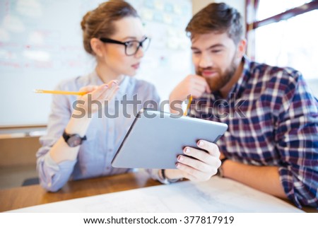 Two business people working with tablet computer in office. Focus on tablet computer