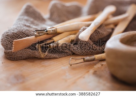 Set of dirty art and craft sculpting tools on wooden table in pottery workshop