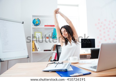 Beautiful businesswoman stretching hands in office