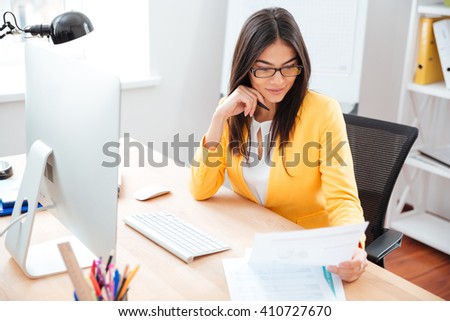 Businesswoman reading paper at her workplace in office