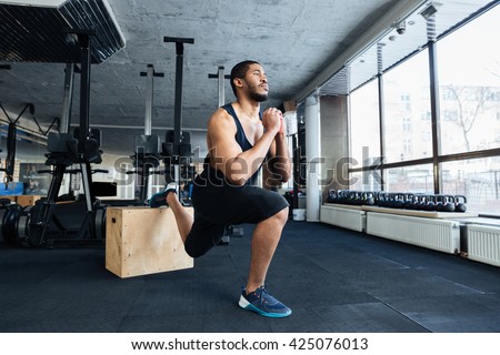 Muscular fitness man doing squats using wooden stand in the gym
