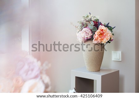 Vase with beautiful fresh flowers standing on small table