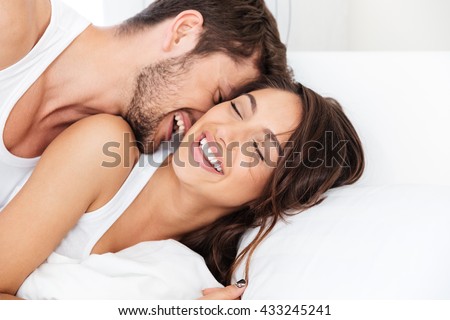 Young happy couple lying together in bed