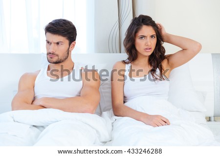 Unhappy separate couple lying in a bed at home