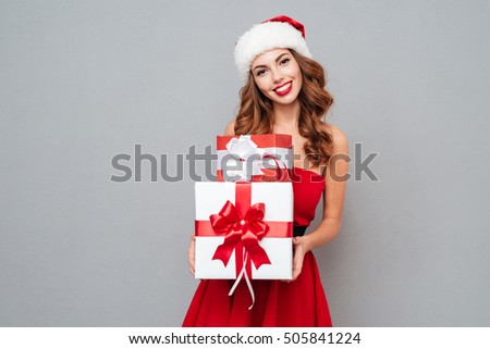Smiling woman with big and small gift. Women on dress and santa\'s hat. Santa\'s helper