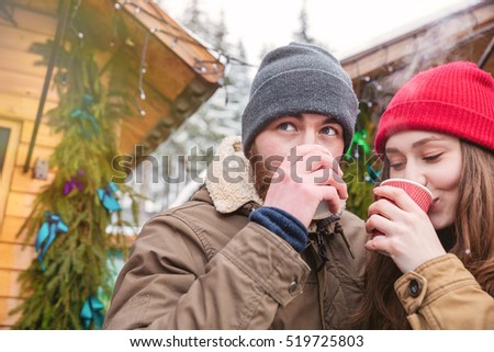 Handsome man and pretty young woman drinking hot coffee on traditional christmas market