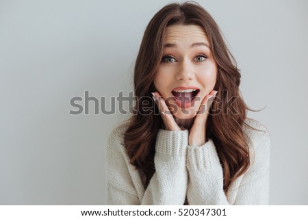 Surprised model in sweater in studio. looking at camera. isolated gray background