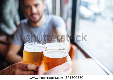 Male friends clinking with beer mugs in pub