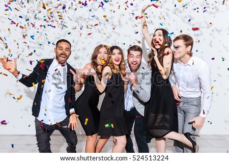 Group of cheerful joyful young people standing and celebrating together over white background