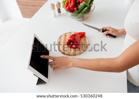 Cropped picture of young woman reading recipe from tablet computer.