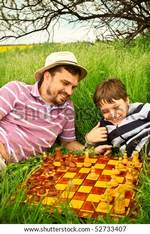 Father and son playing chess outdoors