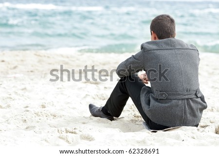 A businessman sitting on the beach alone enjoying the view