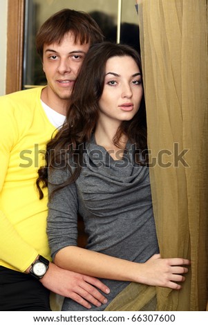 Young happy couple standing near the window at home. Night time.