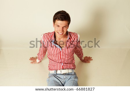 smiling young man sitting on the floor isolated